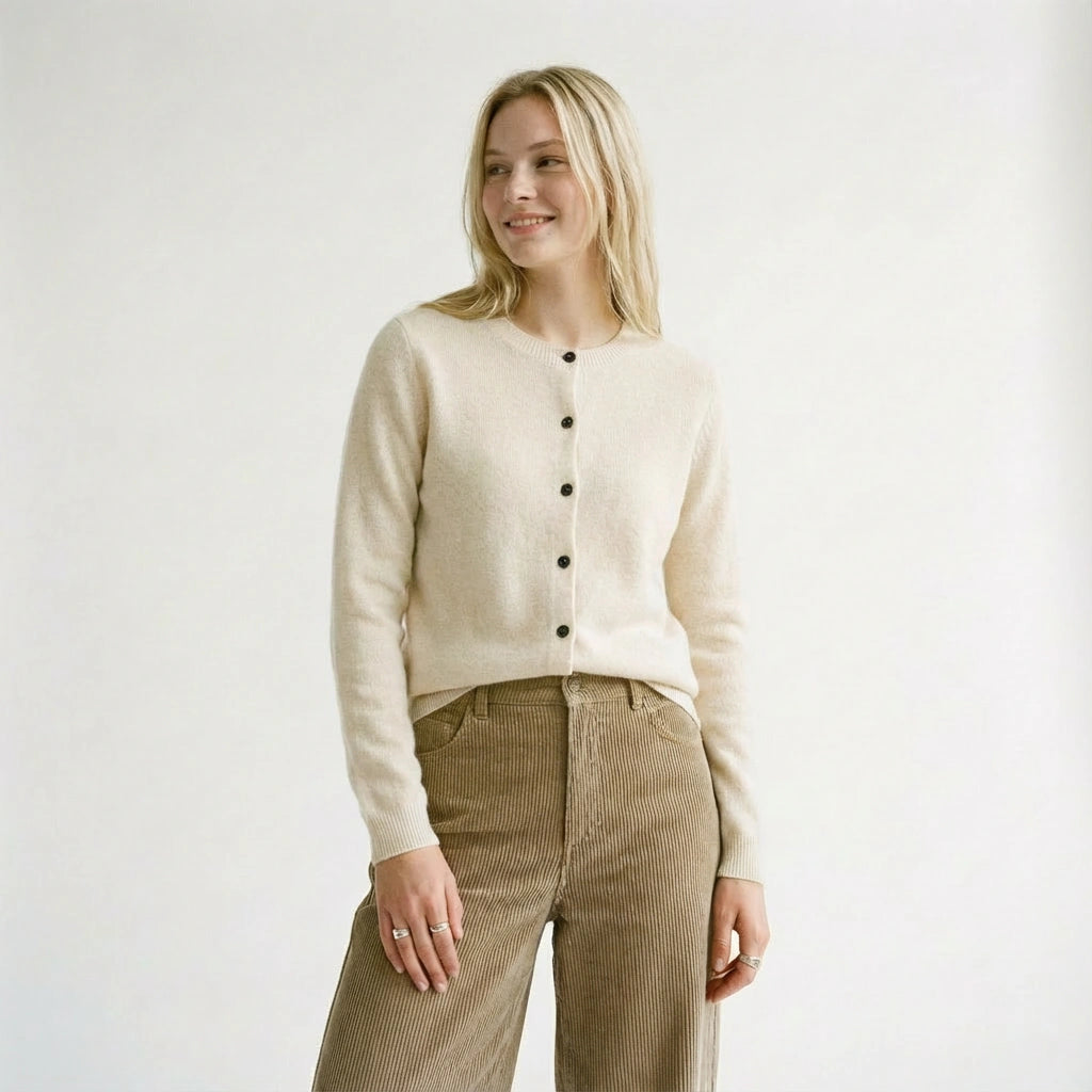 Woman wearing a beige wool cardigan and brown pants on a white background