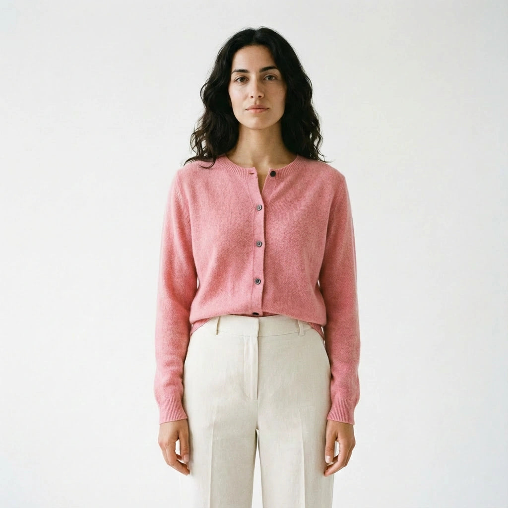 Spanish woman wearing a pink merino wool cardigan and white pants against a plain background