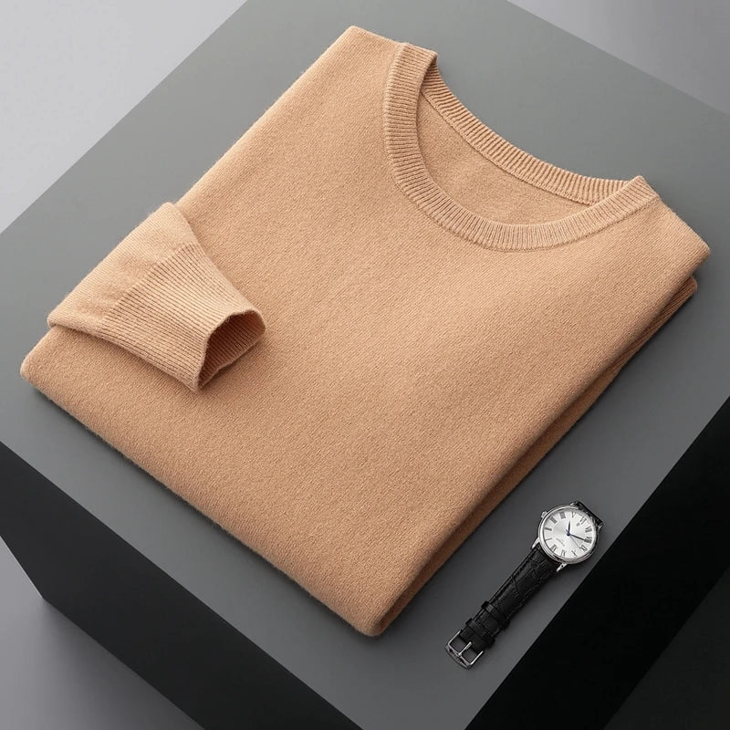 Folded brown brexton men's merino wool sweater on a gray surface with a black watch.