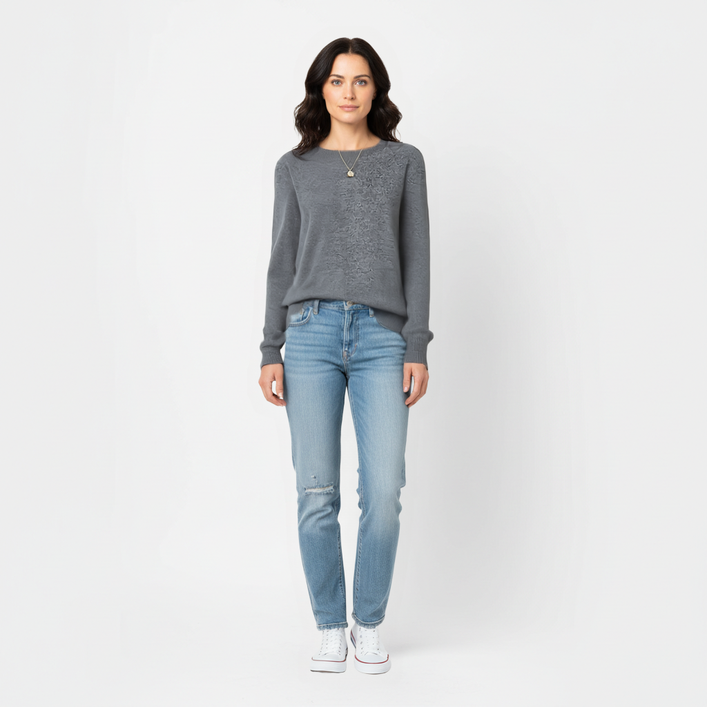 Woman wearing a grey meredith merino wool sweater and light blue jeans on a white background