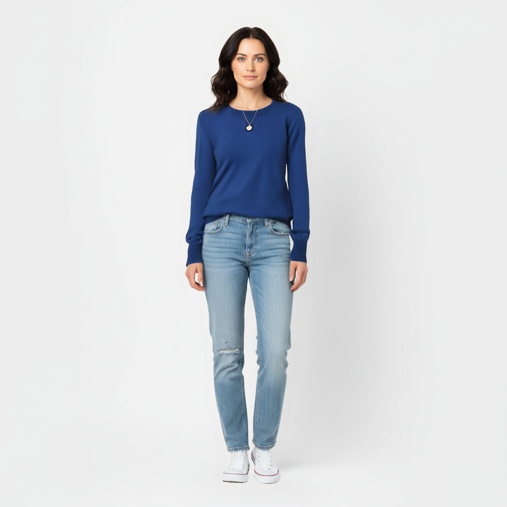 Woman wearing a navy blue meredith merino wool sweater and light blue jeans on a white background