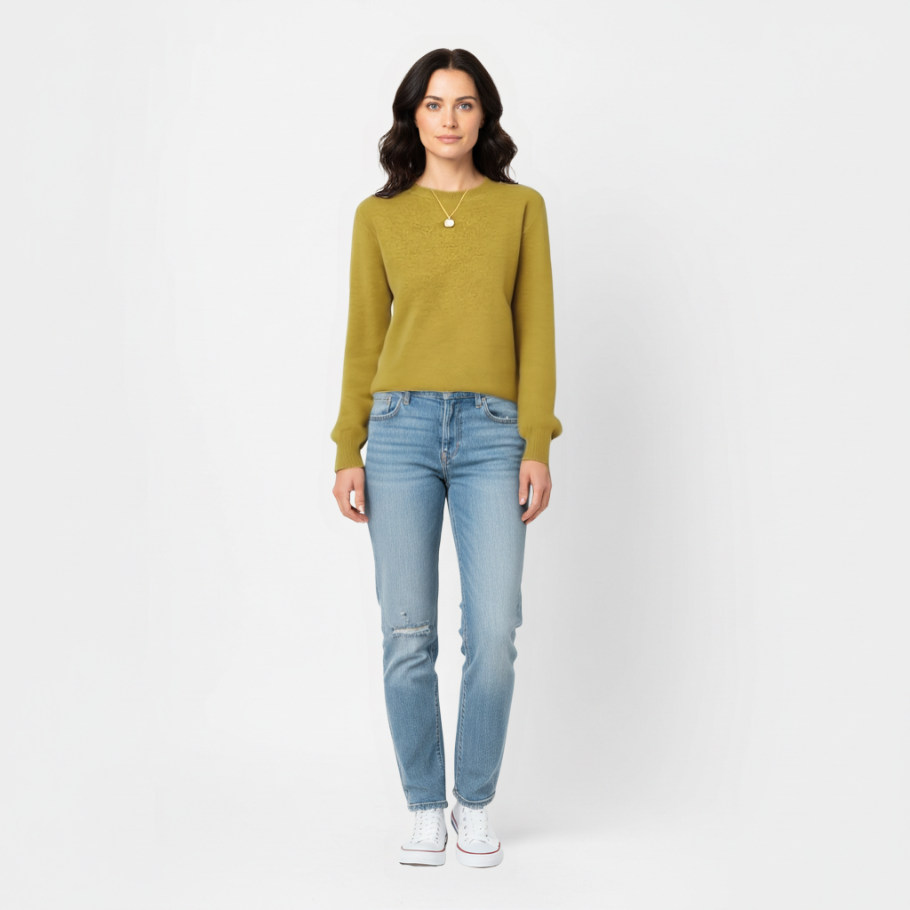 Woman wearing an olive meredith merino wool sweater and light blue jeans on a white background