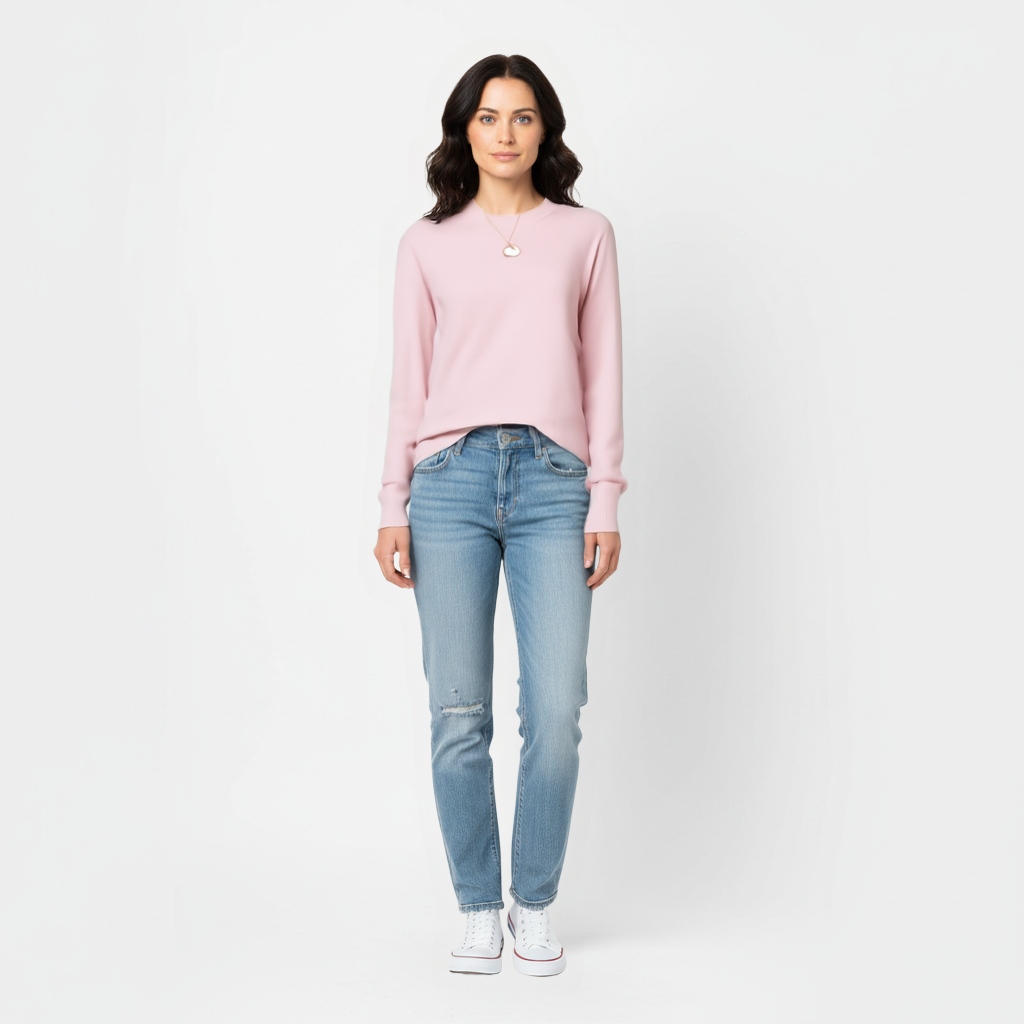 Woman wearing a pink meredith merino wool sweater and light blue jeans on a white background