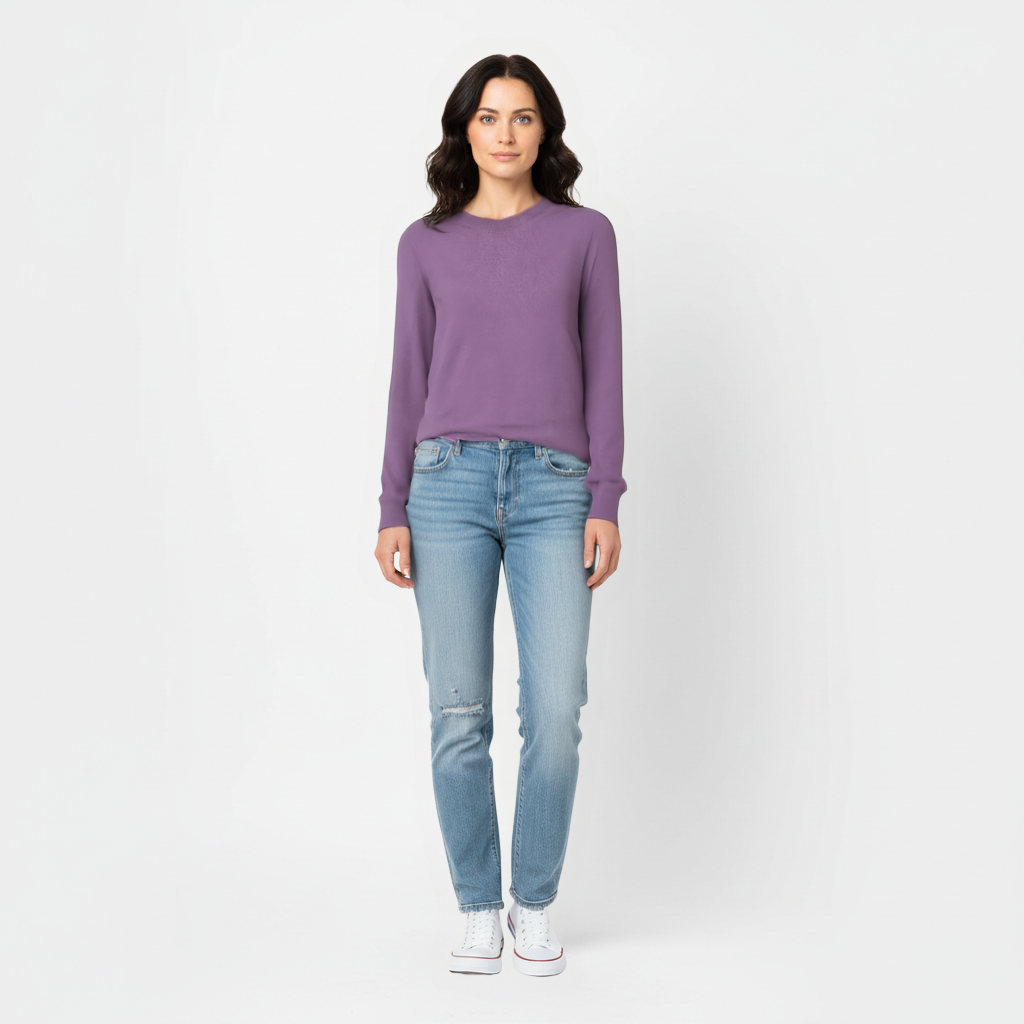 Woman standing wearing a purple meredith merino wool sweater and light blue jeans on a white background